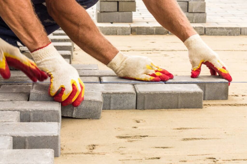 Contractor installing concrete pavers for patio construction on a leveled sand base in Shaker Heights, OH