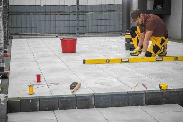 Contractor using a level tool to align large concrete patio slabs during installation in Parma Heights, OH