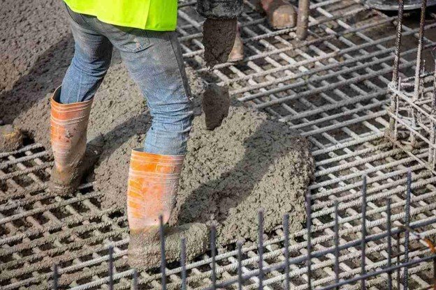 Worker pouring fresh concrete over steel rebar grid for structural slab construction in Parma Heights, OH